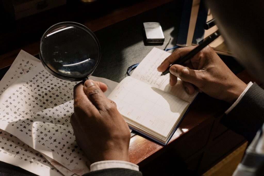 Close-up of a person inspecting the underside of a houseplant leaf with a magnifying glass